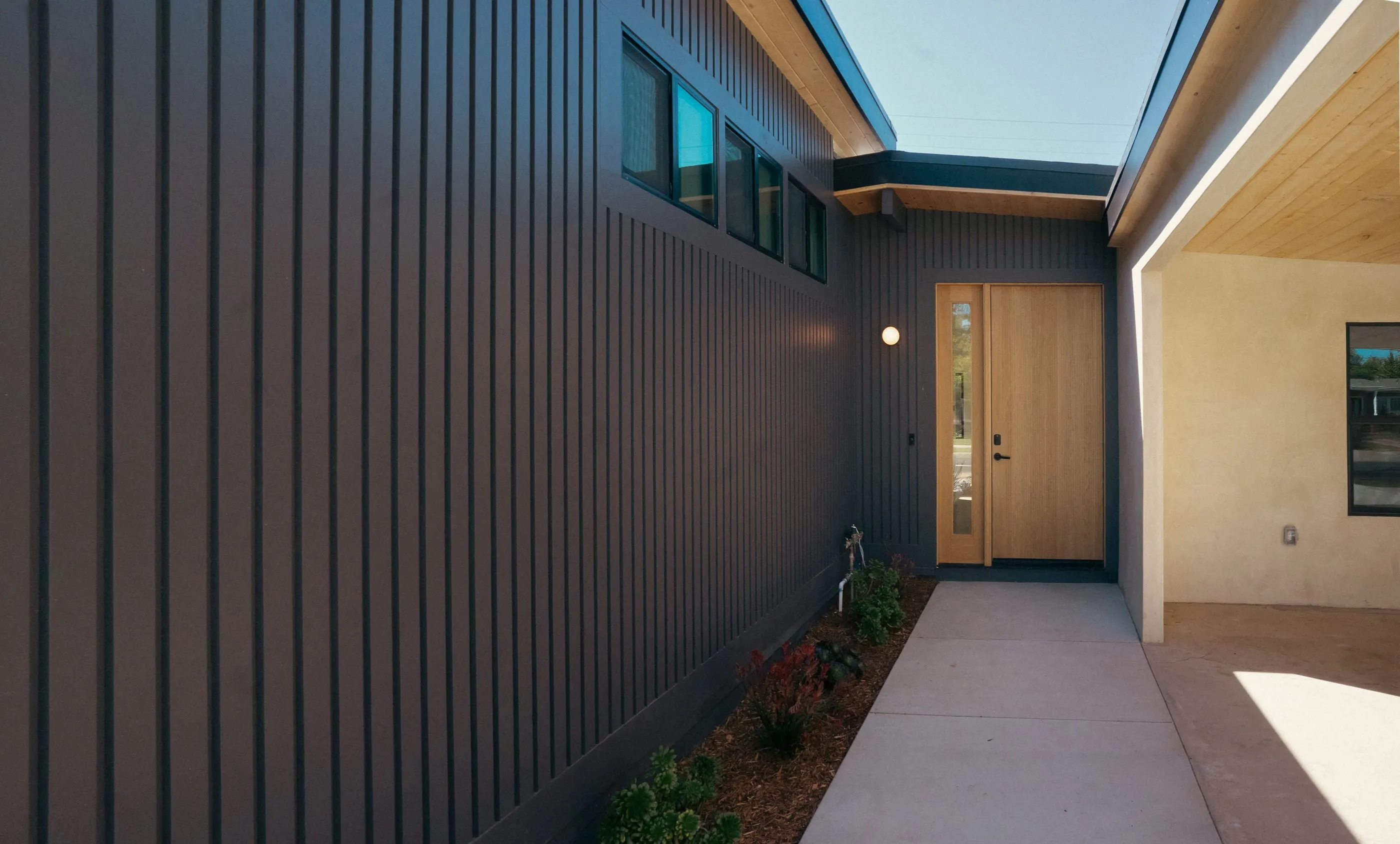 Covered entry courtyard alongside dark vertical siding and clerestory windows