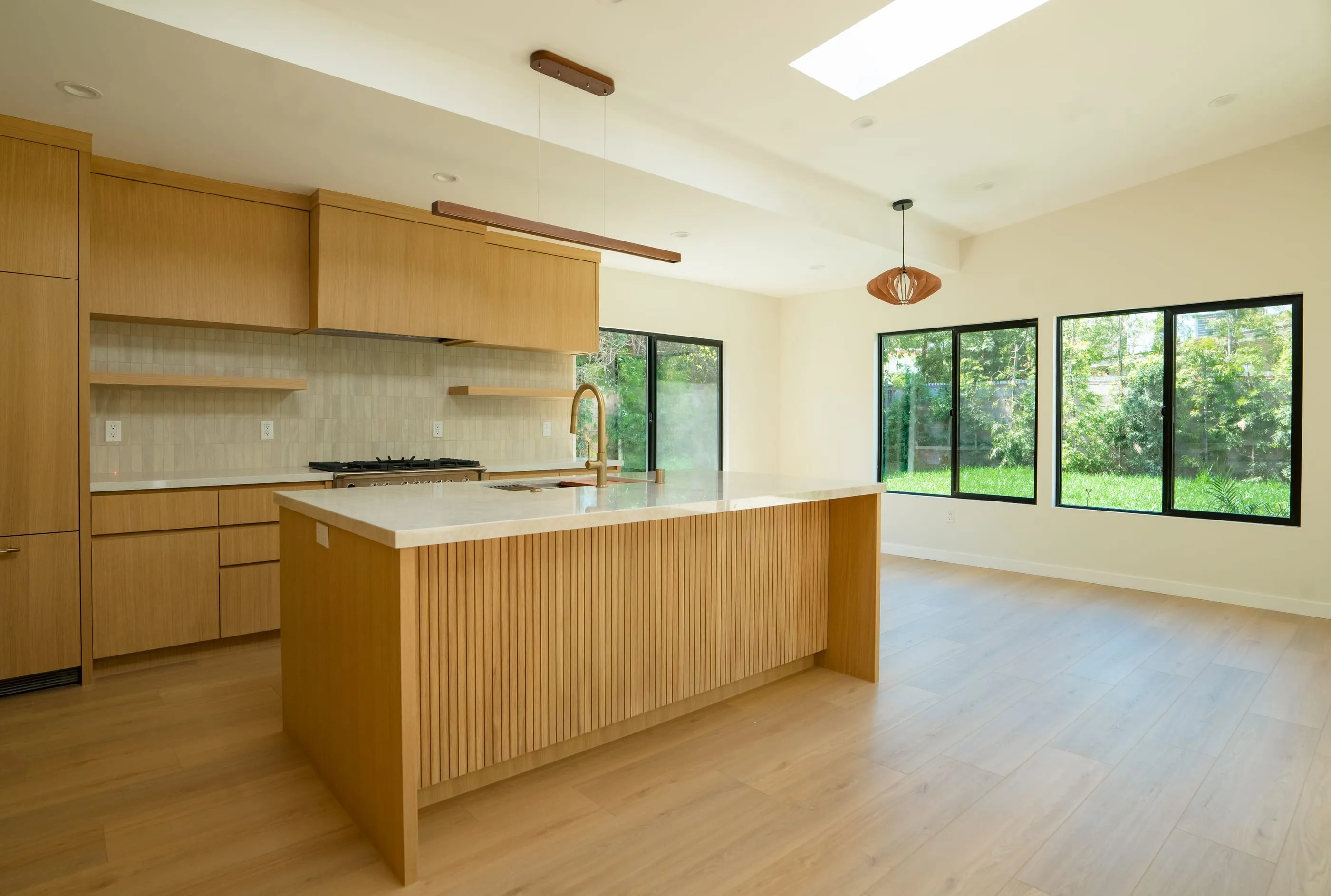 Kitchen island opening toward a wall of black-framed garden windows