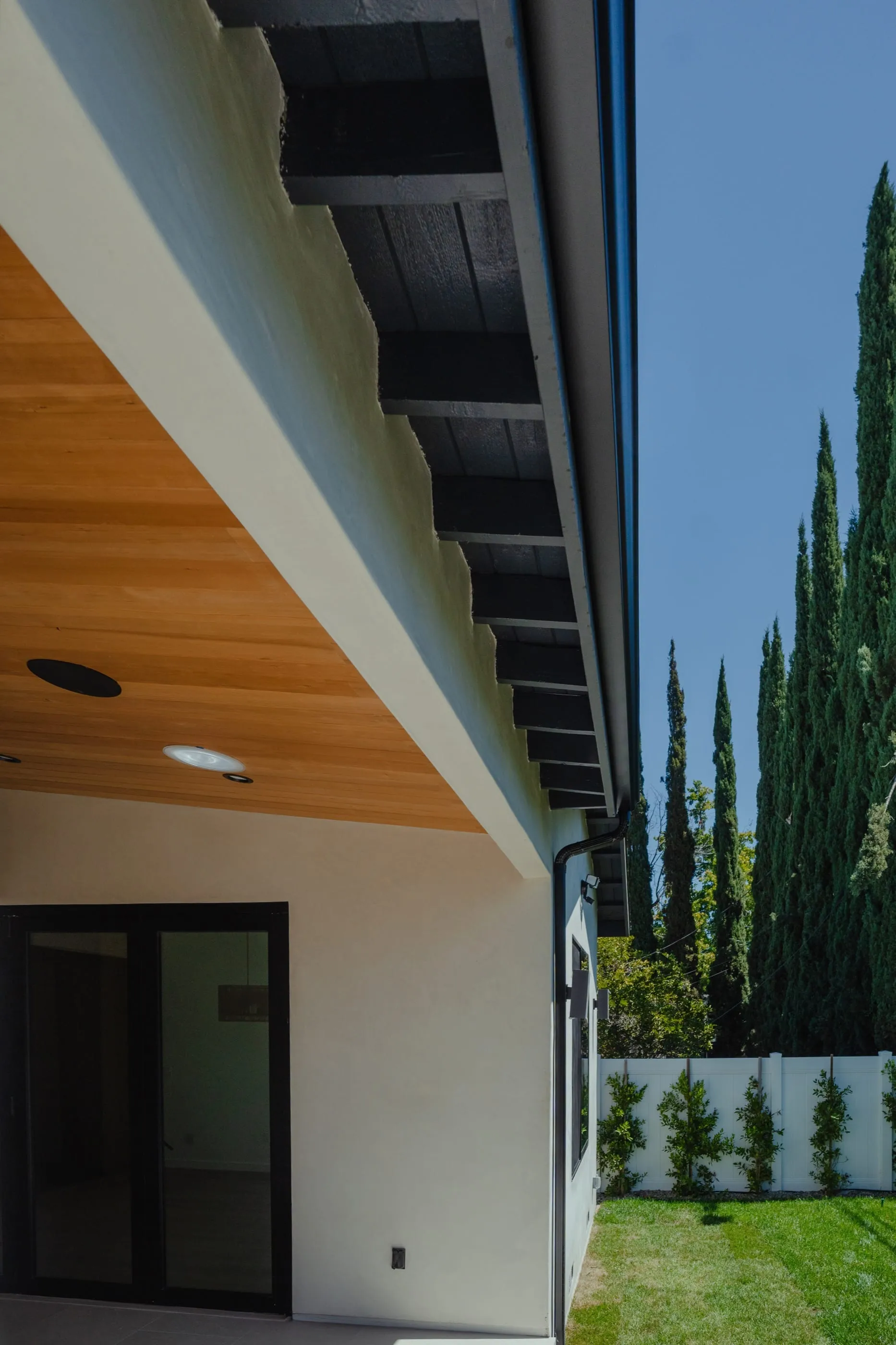 Deep exterior eave with a wood soffit against tall cypress trees