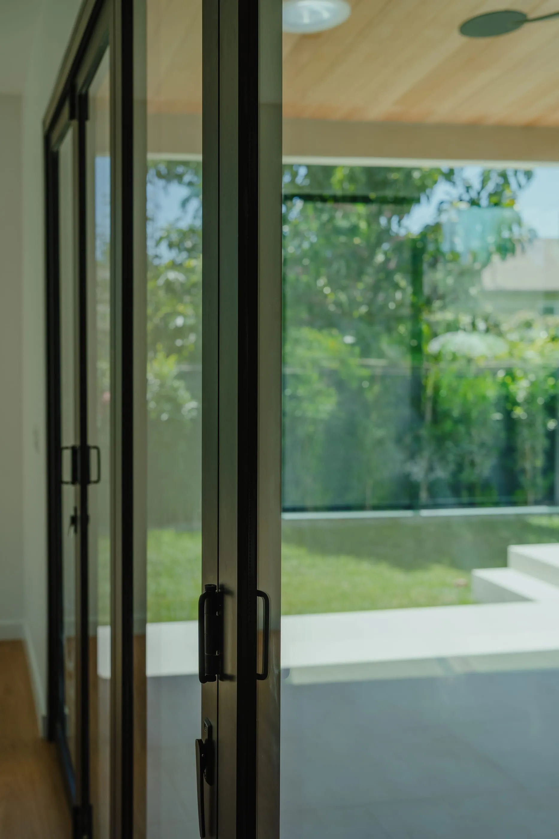 Close view of the dark metal folding-door frame looking toward the courtyard garden