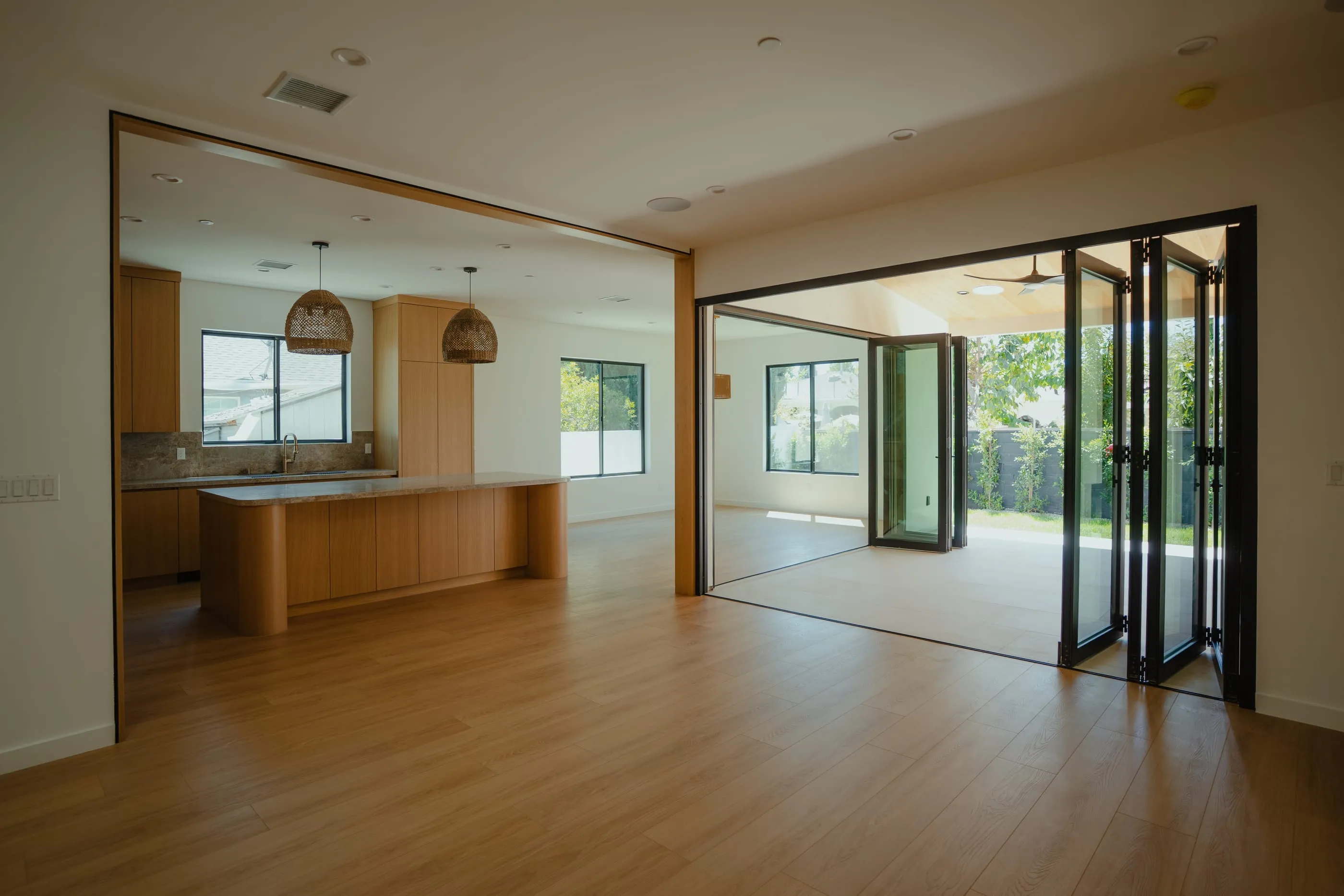 Oak kitchen and living space opening through folding glass doors to the covered courtyard