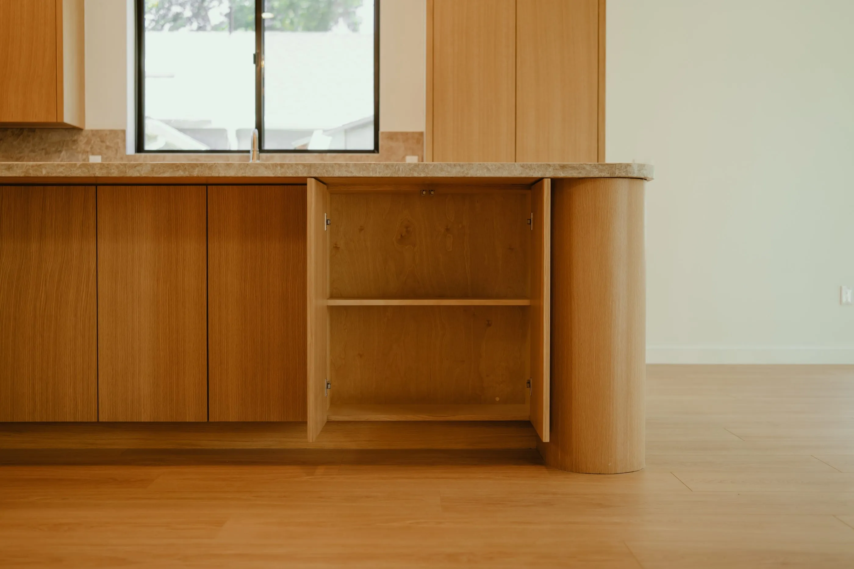 Low view of custom oak island millwork with an open cabinet