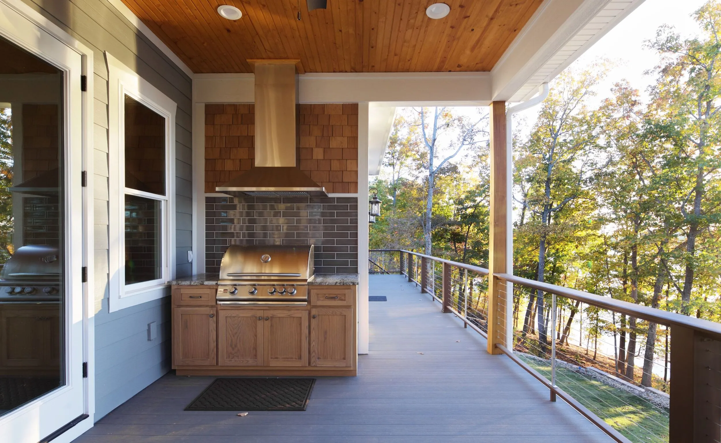 Covered deck with an outdoor kitchen overlooking trees