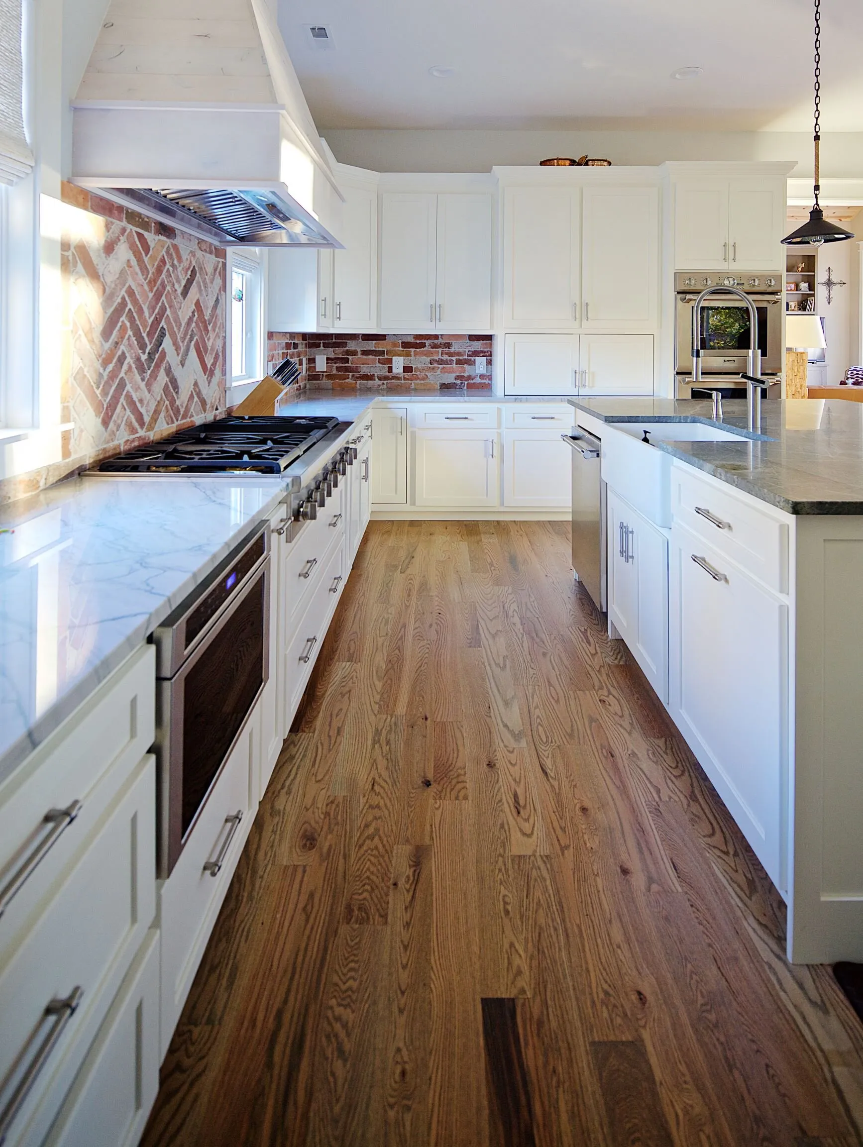 Long bright kitchen with white cabinetry and wood floor