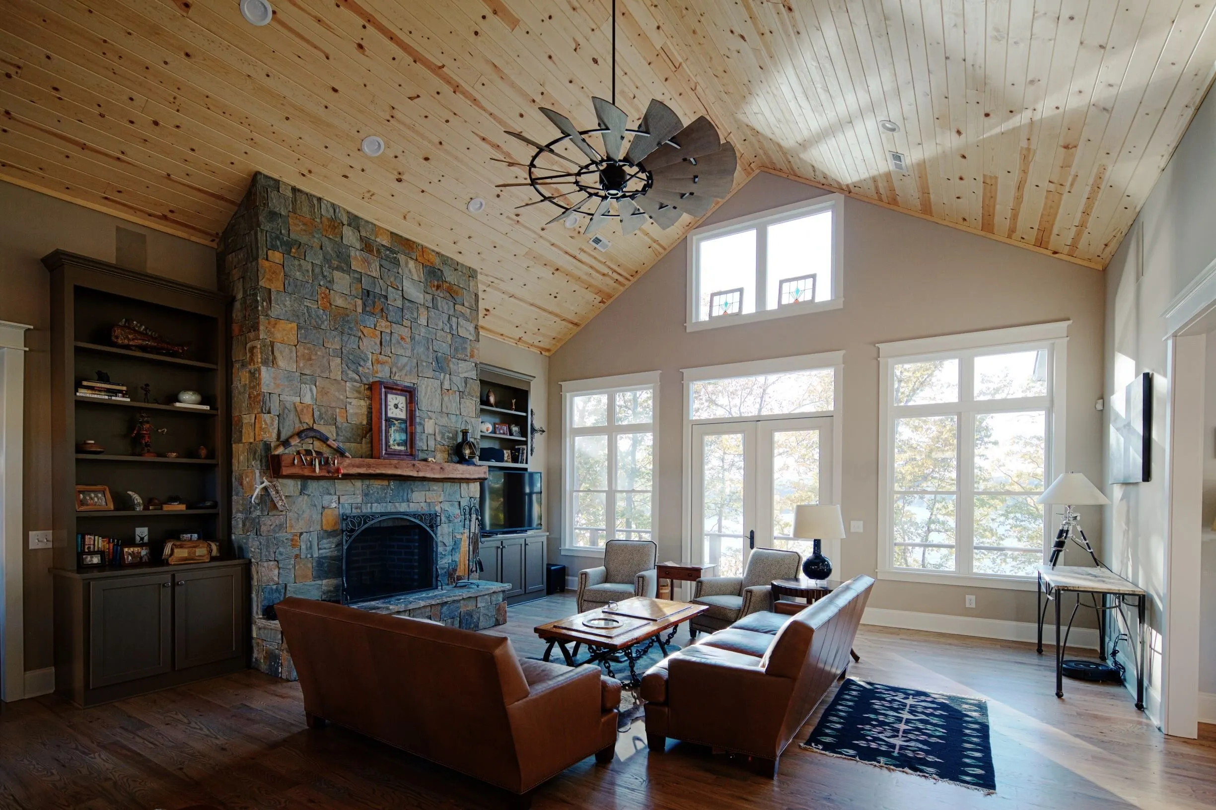 Living room with a stone fireplace and tall lake-facing windows