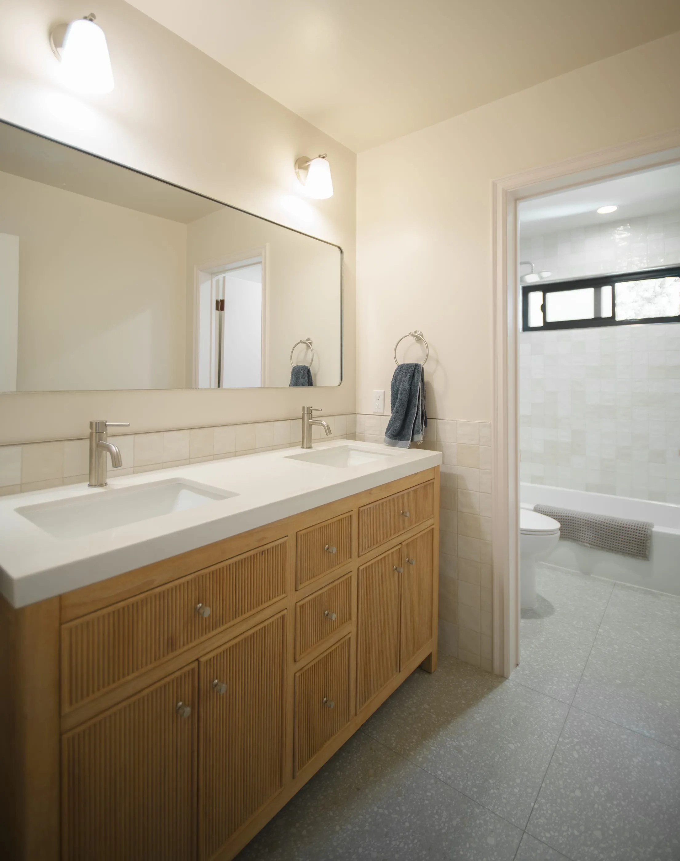 Oak double vanity with reeded cabinet fronts and a long wall mirror
