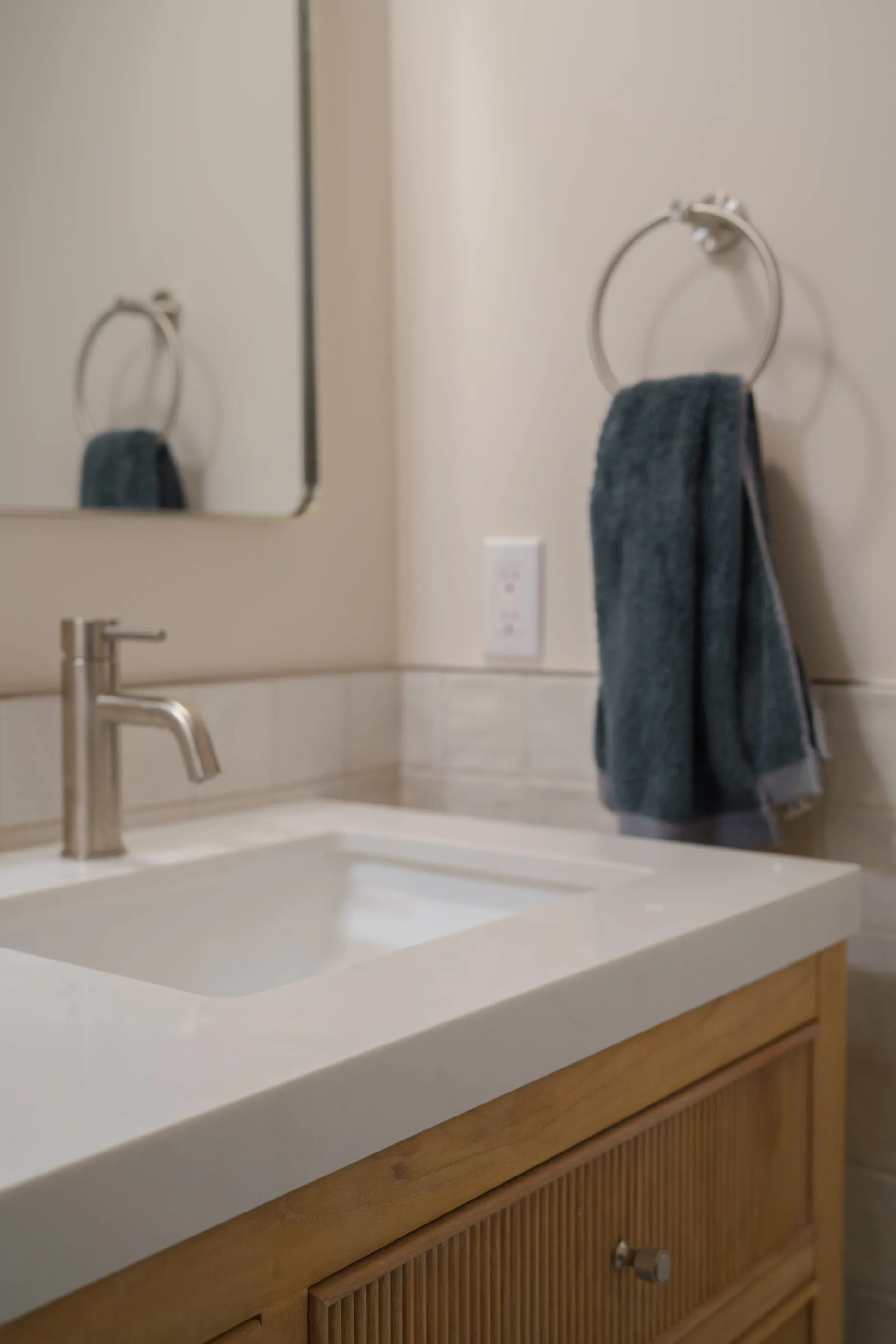 Second bathroom vanity with an oak cabinet, white integrated sink, and blue towels