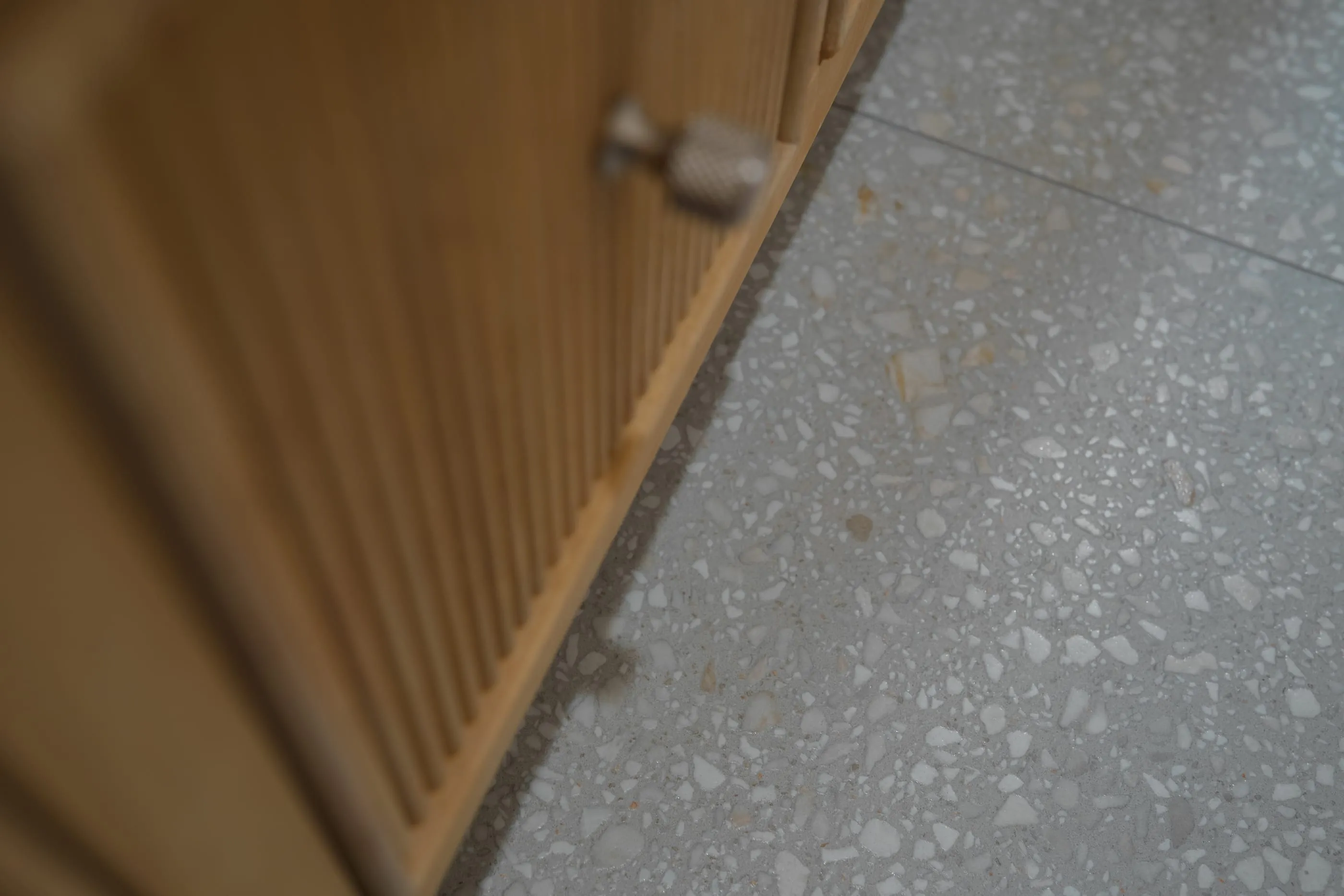 Reeded oak vanity front beside a terrazzo-like floor